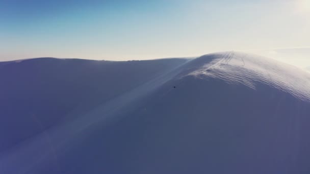 Ein schneller Mann auf einem Motorschlitten fährt bei strahlendem Sonnenuntergang einen verlassenen Hang eines schneebedeckten Berges hinunter — Stockvideo