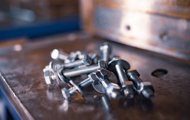 Kapalı metal krom cıvatalar ve kaotik bir düzende fındıklar makinenin parlak metal yüzeyinde yatar. Yedek parça konseptini onar