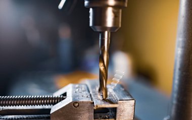 Bir alet çilingirinin iş yerinde talaşı yakın çekim, sondaj makinesi ile sondaj işlemi