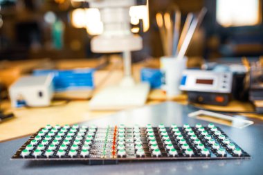 Büyük elektron mikroskobu ve LED ışık göstergeleri bir laboratuarda elektronik bileşenler araştırmasına hazırlanmak için plakaya istiflenmiştir.