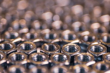 Bal peteği şeklinde yakın plan krom metal fındıklar yan yana uzanarak bir alan oluştururlar. Bağlayıcılar ve inşaat konuları için arka plan konsepti. Yedek parça konseptini onar