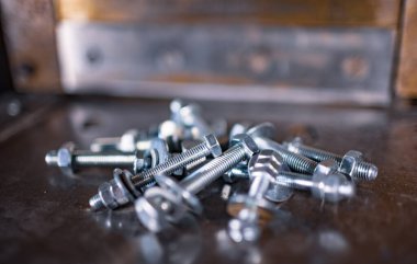 Kapalı metal krom cıvatalar ve kaotik bir düzende fındıklar makinenin parlak metal yüzeyinde yatar. Yedek parça konseptini onar