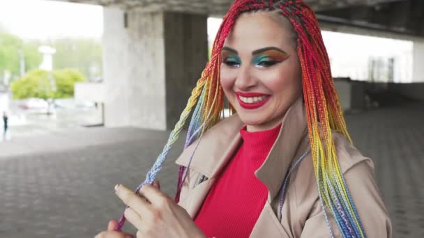 Модная девушка в пиджаке выпрямляет свои цветные африканские косы — стоковое видео