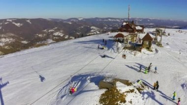 Karlı bir dağ yamacında eski bir kayak istasyonu Kayak ve snowboard yapan bir sürü insan var