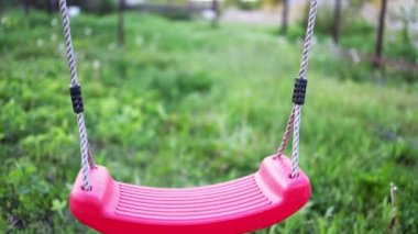 Baharda yeşillik ve ağaçlarla dolu bir bahçede sallanan yalnız bir salıncak.
