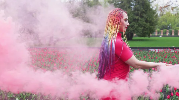 Een meisje met make-up met regenboog vlechten in rode jurk poseren in rode jurk — Stockfoto