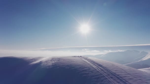Un hombre rápido en una moto de nieve monta una pendiente desierta de una montaña nevada en una puesta de sol brillante — Vídeos de Stock