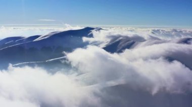 Kış günbatımında tüylü bulutlarla kaplı sıradışı bir dağ vadisi.