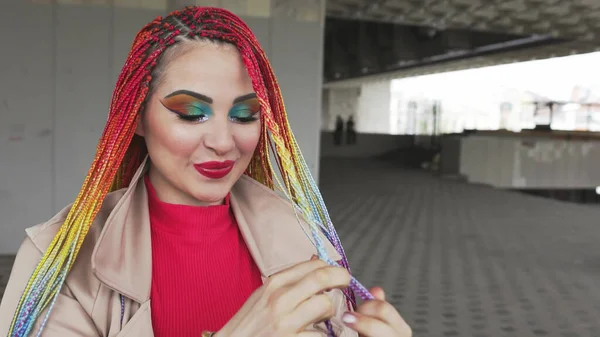 Chica de moda en una chaqueta endereza sus trenzas africanas de color —  Fotos de Stock