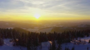 Sıradışı bir vadi tepeler ve dağlarla kaplı köknar ormanlarıyla parlak, alevli bir günbatımının arka planına karşı