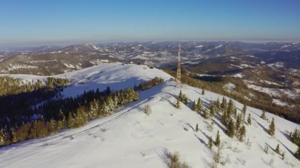 Пролетая над башней радиосвязи, покрытой снегом горы зимний пейзаж. — стоковое видео