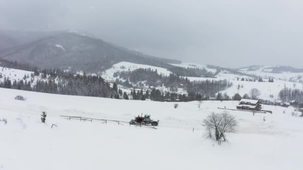 De trekker verwijdert sneeuw van de besneeuwde weg zodat de auto 's kunnen passeren — Stockvideo