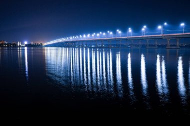 Köprünün altındaki Dinyeper nehrindeki parlak fenerlerin yansıması.