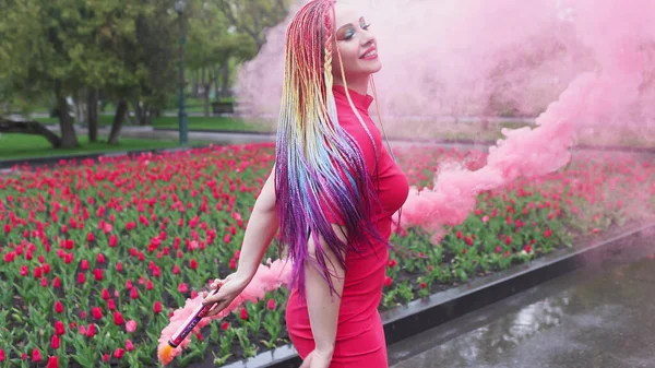 Een meisje met make-up met regenboog vlechten in rode jurk poseren in rode jurk — Stockfoto