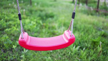 Baharda yeşillik ve ağaçlarla dolu bir bahçede sallanan yalnız bir salıncak.