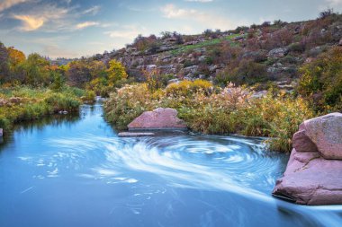 Ukrayna 'nın pitoresk doğası üzerine serin bir sonbaharda, sararmış altın otlarla kaplı beyaz ıslak taşların arasında fantastik bir dere akıyor.