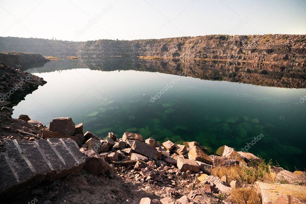 A very small beautiful lake surrounded by large heaps of stone waste from hard work in the mine