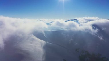 Kış günbatımında tüylü bulutlarla kaplı sıradışı bir dağ vadisi.