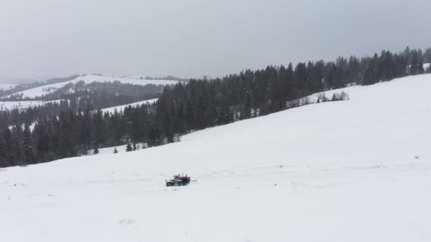 Трактор убирает снег с заснеженной дороги, чтобы машины могли проехать — стоковое видео