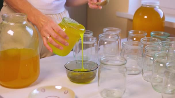 Γυναίκα ρίχνει μέλι σε διαφανή βάζα σε ένα λευκό τραπέζι — Αρχείο Βίντεο