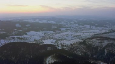 Sıradışı bir vadi tepeler ve dağlarla kaplı köknar ormanlarıyla parlak pembe bir günbatımının arka planına karşı