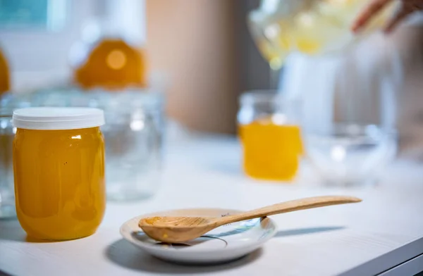 Alguien vierte miel en frascos transparentes sobre una mesa blanca — Foto de Stock