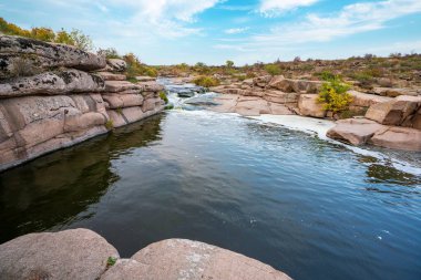Pürüzsüz ve karanlık taşların arasında küçük parlak bir dere akıyor.