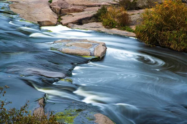 A small shining stream flows among smooth wet and dark stones — Stock Photo, Image