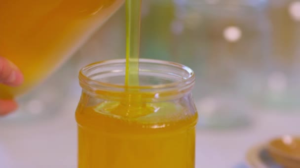 Woman pours honey into transparent jars on a white table — Stock Video