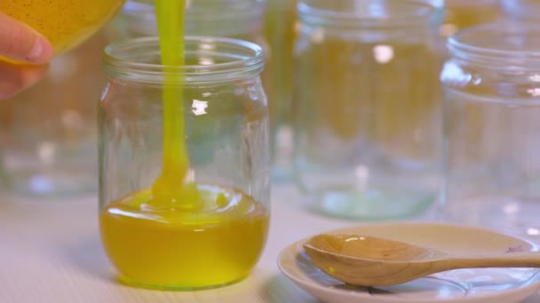 Woman pours honey into transparent jars on a white table — Stock Video