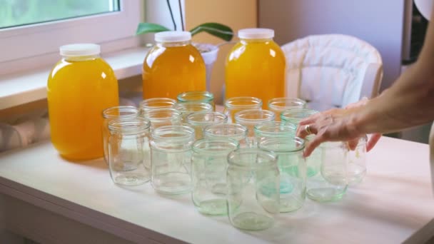 Mujer vierte miel en frascos transparentes sobre una mesa blanca — Vídeo de stock