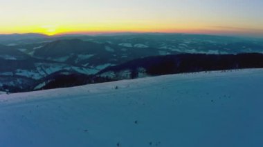 Sıradışı bir vadi tepeler ve dağlarla kaplı köknar ormanlarıyla parlak, alevli bir günbatımının arka planına karşı