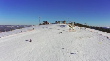 Karlı bir dağ yamacında eski bir kayak istasyonu Kayak ve snowboard yapan bir sürü insan var
