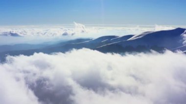 Kış günbatımında tüylü bulutlarla kaplı sıradışı bir dağ vadisi.
