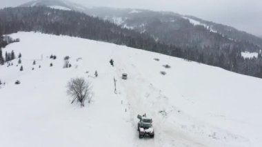 Traktör karla kaplı yoldan karları kaldırır böylece arabalar geçebilir.