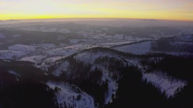 Sıradışı bir vadi tepeler ve dağlarla kaplı köknar ormanlarıyla parlak, alevli bir günbatımının arka planına karşı