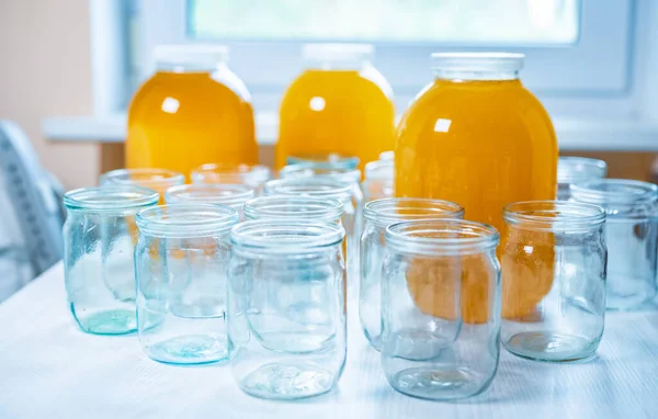 Zusammensetzung einer großen Anzahl von Gläsern und drei Gläsern Honig, die auf einem weißen Tisch vor einem hellen Hintergrund stehen — Stockfoto