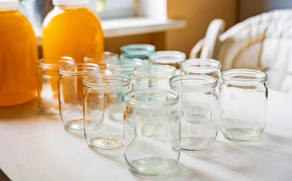 Composition of a large number of jars and three jars of honey standing on a white table against a background of light — Stock Photo, Image