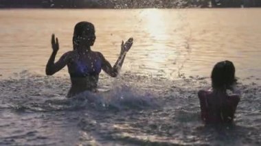 Gün batımında gölde oynayan iki kız kardeş.