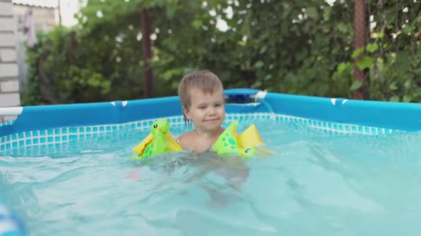 穿套头衫的孩子在院子里的游泳池里游泳 — 图库视频影像