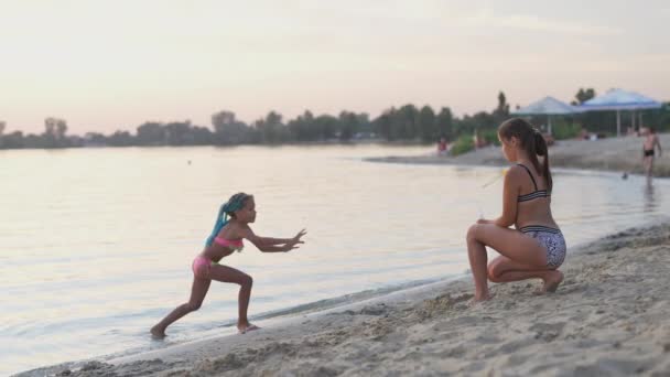 Menina engraçada pega bolhas na margem do lago, que sua irmã mais velha deixa ir — Vídeo de Stock