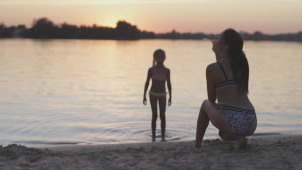 Lustiges Mädchen fängt Blasen am Ufer des Sees, die ihre ältere Schwester loslässt — Stockvideo