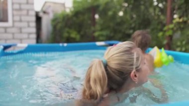 Annem havuzda kolsuz çıplak bir bebekle oynuyor yaz günbatımının arka planında.