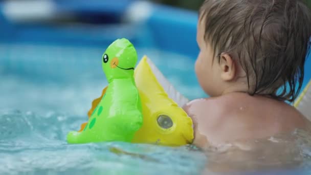 Üst kollu çocuk bahçedeki havuzda yüzüyor. — Stok video
