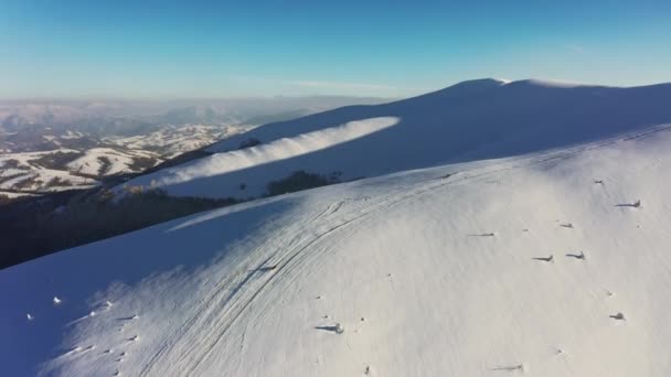 Um homem rápido em um snowmobile monta uma encosta deserta de uma montanha nevada em um pôr do sol brilhante — Vídeo de Stock