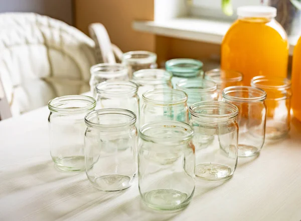 Composition of a large number of jars and three jars of honey standing on a white table against a background of light — Stock Photo, Image