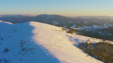 Sıradışı bir vadi tepeler ve dağlarla kaplı köknar ormanlarıyla parlak pembe bir günbatımının arka planına karşı