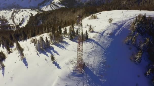 Voando sobre a torre de comunicações de rádio, neve de montanha coberto paisagem de inverno. — Vídeo de Stock