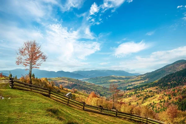 Pueblo bajo las colinas protegidas por los bosques de otoño a la luz del sol brillante en buen tiempo —  Fotos de Stock