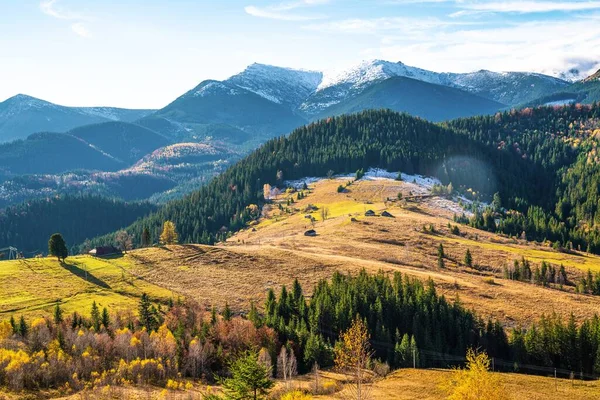 カルパチア山脈と暖かい秋の空を背景にした小さな村を覆う美しいカラフルな森 — ストック写真